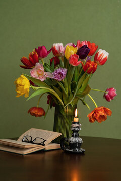 Still life. Vase of colourful tulips on the wooden table - green background