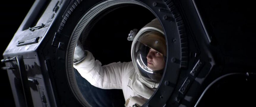 Portrait of Caucasian female astronaut flying towards spaceship cupola window. Space exploration, Mars mission. Shot with 2x anamorphic lens