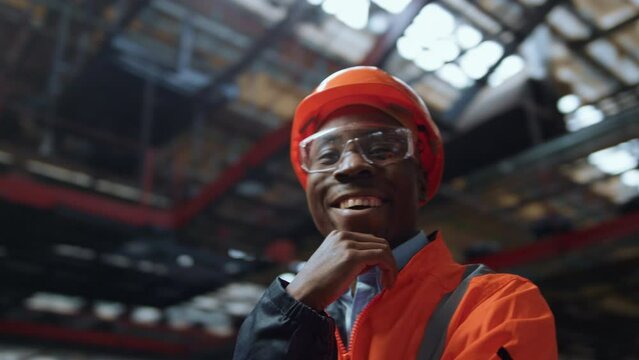 Joyful supervisor looking camera at huge industrial special production warehouse