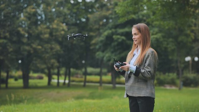 A cute girl controls a drone in the park.