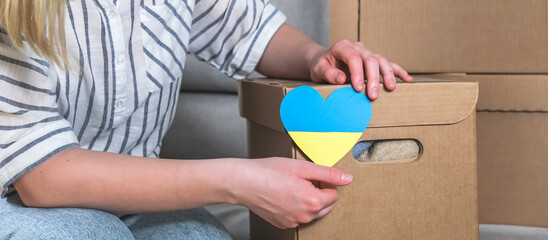 Donations Ukraine, volunteering, charity, war refugees. Girl collects clothes charity for Ukraine Volunteer donations, humanitarian aid, migrants, refugees, aid, charitable organizations..