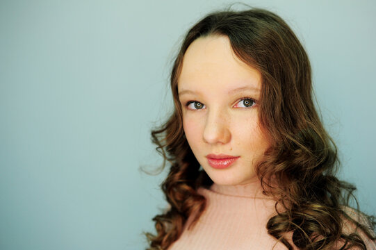 a girl in a make-up studio tinager in pink golf smiles happy with a new makeup in her eyes reflects a lamp for photography gently painted eyelashes and lips hair blonde girl 10-13 years old.