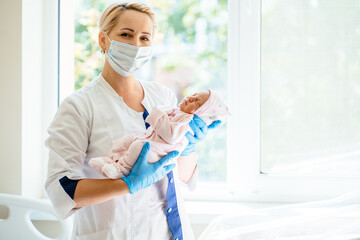 Breastfeeding consultant or doctor, nurse standing in maternity ward and holding newborn baby in...