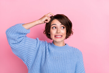 Portrait of stressed hesitant female scratch head look empty space can't remember isolated on pink color background