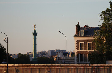 Fototapeta premium View across the Seine to a column in the Place de la Bastille in Paris, at golden hour