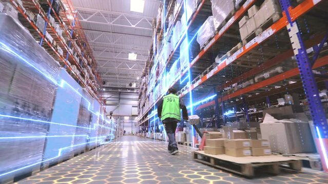 Digitalization of production. A worker is carrying a rokla through a large warehouse. The worker walks through the warehouse. Futuristic production concept.