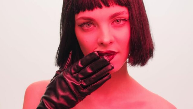Portrait of a girl in red light with black lips and a wig on a white background in the studio. Woman in neon creative light.