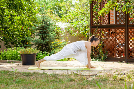 Yoga Practice in the summer garden. Surya Namaskar - Salute to the Sun, Ashva sanchalanasana or rider's pose