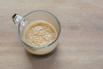 close up view of espresso coffee crema in a glass cup on wooden table in vintage tone.