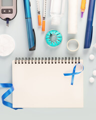 Diabetic composition with glucose meter, test strips for determining blood sugar levels, syringes for insulin injections, sanitizing on a blue background with notebook. Concept of diabetes control