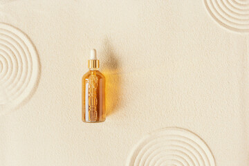 Liquid product package in glass bottle on fine sand. Hyaluronic or polyglutamic acid oil cosmetic...