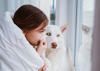 A cold girl blows her nose in a white rag on white background. Rhinitis snot runny nose stuffy nose. Allergy Preteen girl with handkerchief. medical concept