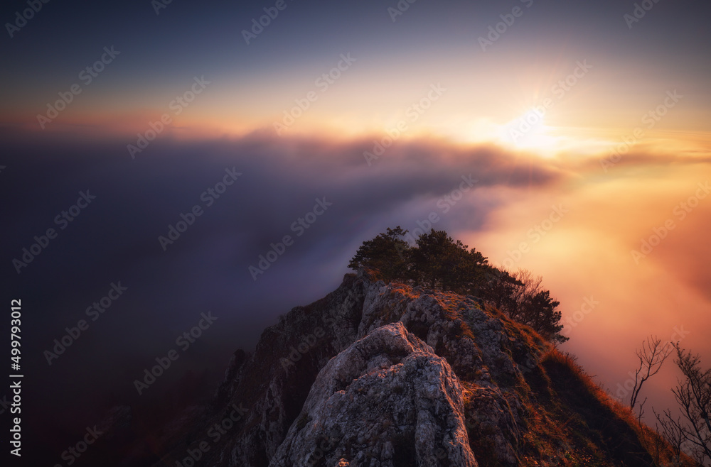 Canvas Prints Sunset hidden behind clouds and fog over hills, bright yellow sun on colorful cloudscape, blue violet orange sky.