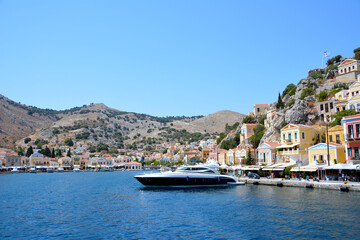 Fototapeta na wymiar boat in seaport of greek island on mountain and coloured houses background