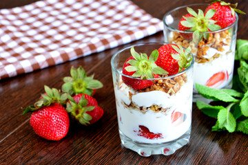 healthy breakfast with muesli, yoghurt and fresh strawberries on kitchen table, close-up