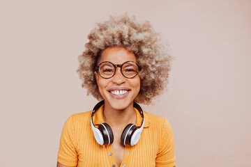 Front view of happy smiling latin american young afro woman listening to music with earphones,...