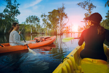 two asian woman sailing sea kayak in mangrove lagoon