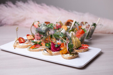 assorted bruschetta and sandwiches on a white plate