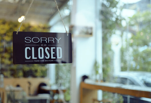 Business coffee cafe shop sign board is hang on door and show "Sorry We are Closed" with cafe and resturant blur bokeh background.