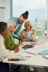 Obraz premium A hipster educator is showing a lesson on the tablet to a multicultural group of senior students in the classroom.