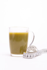 a glass with a green drink and a tape centimeter for weight loss