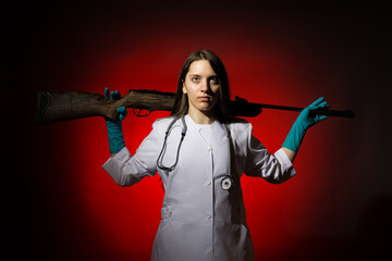a young girl doctor in a white coat put a gun on her shoulders on a dark background