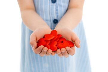 cropped view of blurred girl with handful of red toy hearts isolated on white.