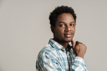 Black unshaven man in plaid shirt posing and looking at camera