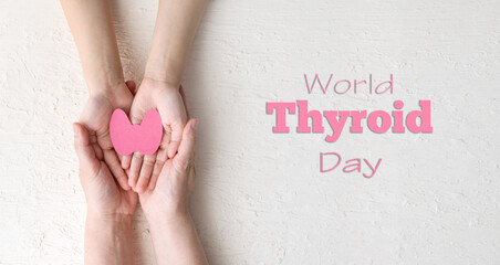 World Thyroid Day. women 's and children 's hands hold paper form of the thyroid gland on a white...