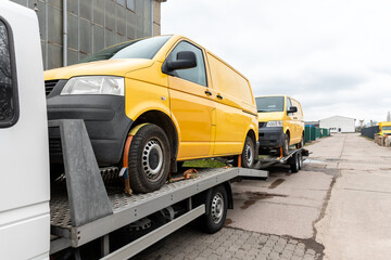 White small cargo truck car carrier loaded with two yellow van minibus on flatbed platform and semi...