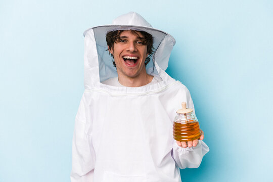Young caucasian beekeeper man isolated on blue background excited keeping ok gesture on eye.