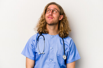 Young nurse caucasian man isolated on blue background dreaming of achieving goals and purposes