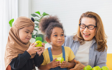 Granddaughters and grandmother enjoying with raw organic green apple, Children and woman biting green apples with smile