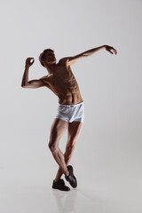 Modern, contemp. Young artistic man, flexible male dancer dancing isolated on grey studio background. Art, motion, flexibility, inspiration concept.