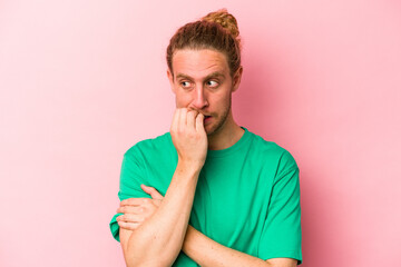 Young caucasian man isolated on pink background biting fingernails, nervous and very anxious.
