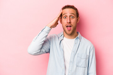 Young caucasian man isolated on pink background shouts loud, keeps eyes opened and hands tense.