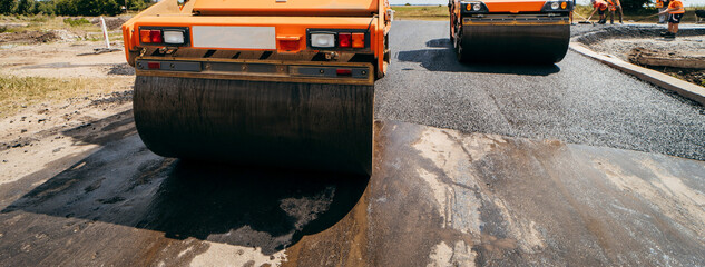 Vibratory asphalt roller compactor compacting new asphalt pavement. Road service repairs the highway