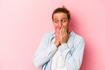 Young caucasian man isolated on pink background laughing about something, covering mouth with hands.