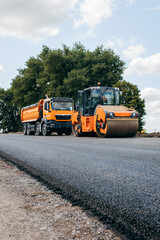 Vibratory asphalt rollers compactor and truckstanding on the side of the road. Road service build a new highway	
