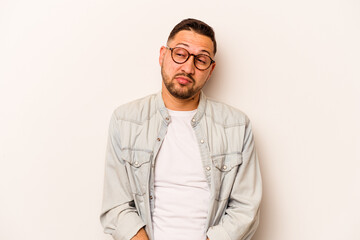 Young hispanic man isolated on white background shrugs shoulders and open eyes confused.