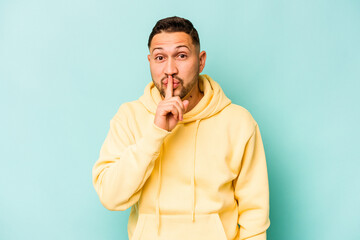 Young hispanic man isolated on blue background keeping a secret or asking for silence.
