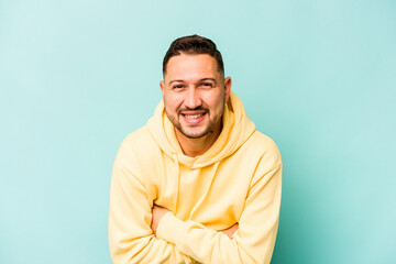 Young hispanic man isolated on blue background laughing and having fun.