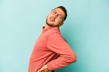 Fototapeta premium Young hispanic man isolated on blue background suffering a back pain.