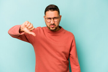 Young hispanic man isolated on blue background showing thumb down and expressing dislike.