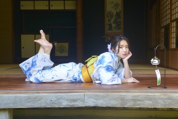 古民家の縁側にたたずむ浴衣姿の若く美しい女性	