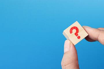 Question mark design on wooden block with copy space on blue background	