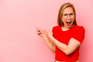 Young caucasian woman isolated on pink background excited pointing with forefingers away.