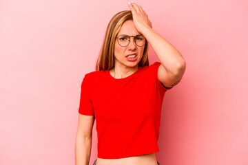 Young caucasian woman isolated on pink background forgetting something, slapping forehead with palm...