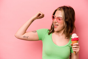 Young caucasian woman holding an ice cream isolated on pink background raising fist after a victory, winner concept.