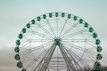 City park with a view of the Ferris Wheel attraction on a spring day, close-up.